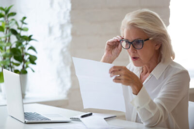 A senior businesswoman, surprised reading a paper